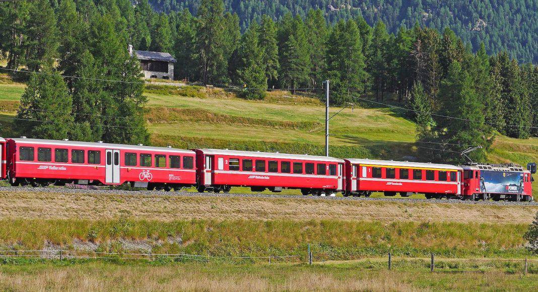 Zug der Rhätischen Bahn fährt durch eine Landschaft im Engadin