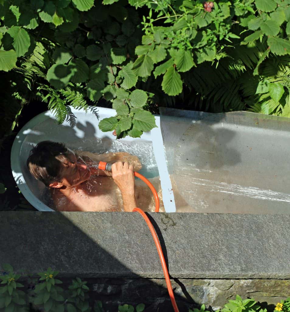 Mensch sitzt im Garten in einer Wanne und geniesst das kalte Wasser.