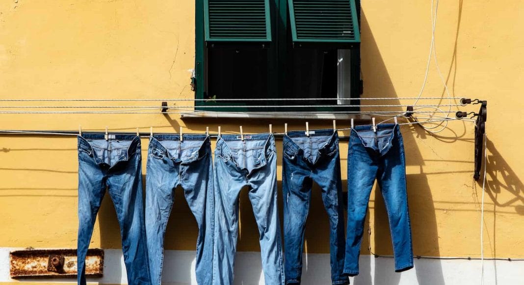 Jeans hängen an einer Wäscheleine vor einer Hauswand. Viele Chemikalien werden zur Herstellung von Jeans benötigt.