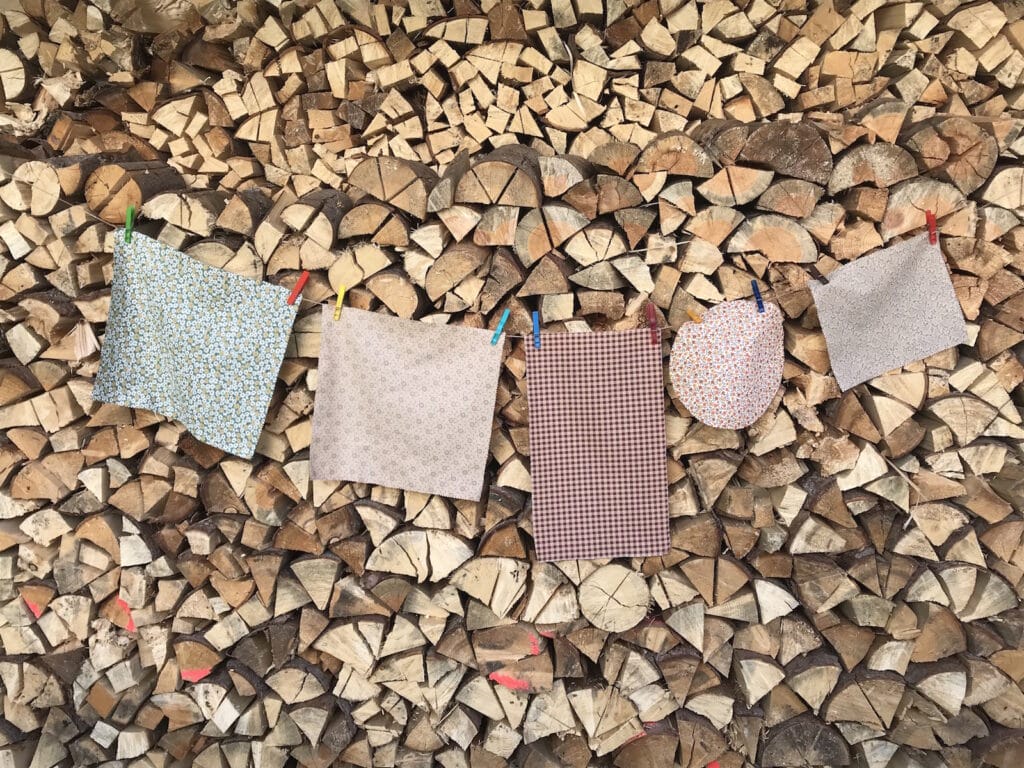 Bienenwachstuecher an Waescheleine vor Holzbeige